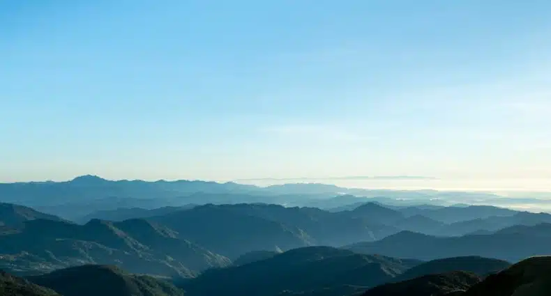 Paisagem de montanhas com vegetação exuberante e céu azul claro em dia ensolarado