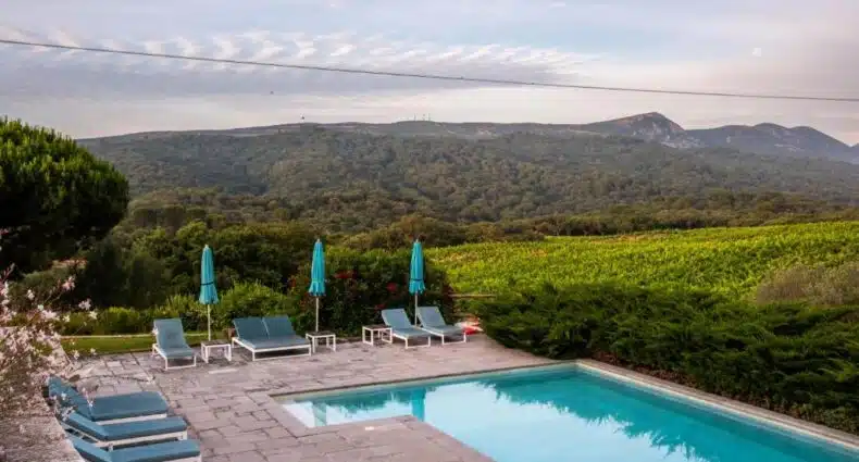 Piscina de borda infinita com espreguiçadeiras em área externa com vista para montanhas e vinhedo no Hotel Casa Palmela, uma das dicas de onde ficar em Setúbal.
