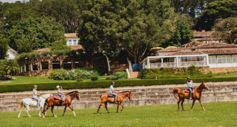 Passeio a cavalo em área rural com construção colonial ao fundo da Hotel Fazenda Dona Carolina, em São Paulo, na cidade de Itatiba
