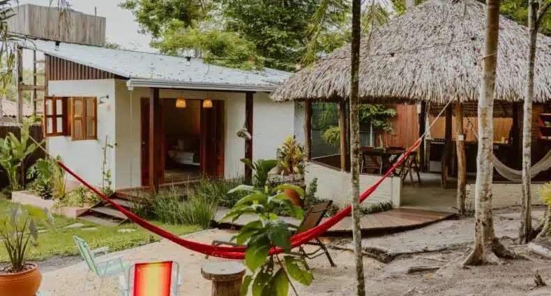 Casa de campo com rede vermelha em jardim tropical, ideal para descanso e ecoturismo