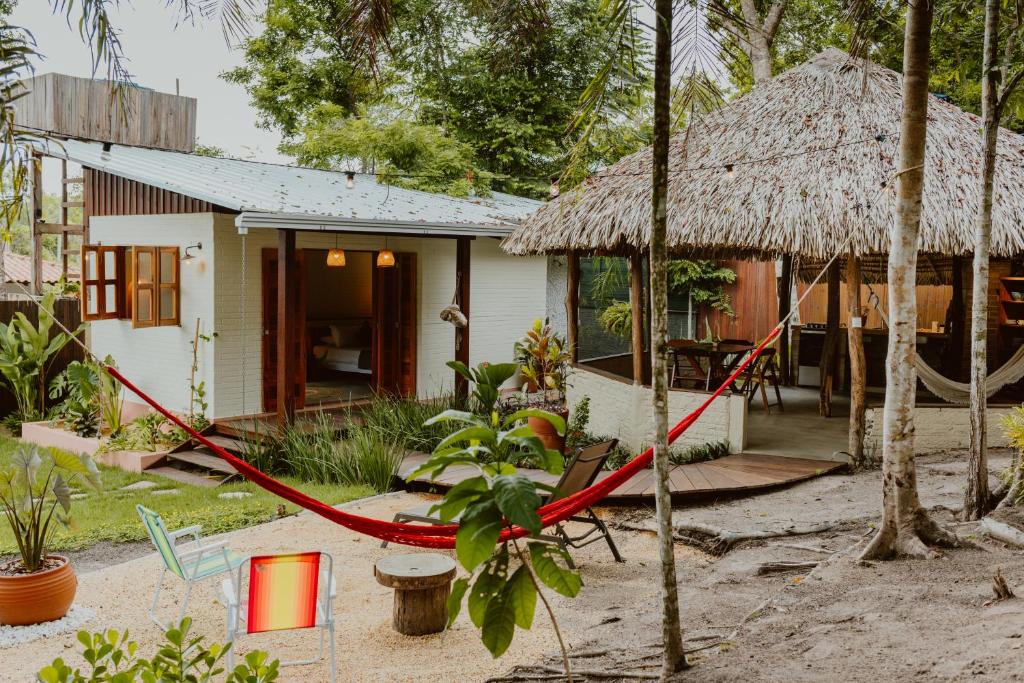 Casa de campo com rede vermelha em jardim tropical, ideal para descanso e ecoturismo. Ilustra o post de chalés em Alter do Chão.
