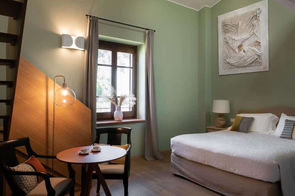 Quarto de hotel aconchegante com cama de casal, mesa e cadeira de madeira, decoração moderna e iluminação amarela. Ilustra onde ficar na Sardenha.
