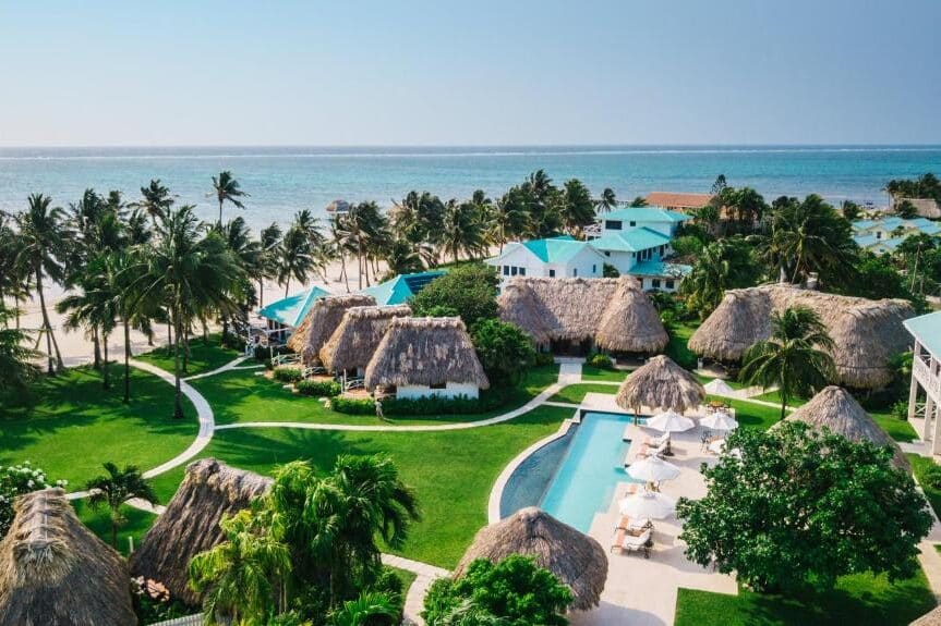 Resort de luxo com bangalôs de teto de palha e piscina à beira-mar em praia paradisíaca de San Pedro.