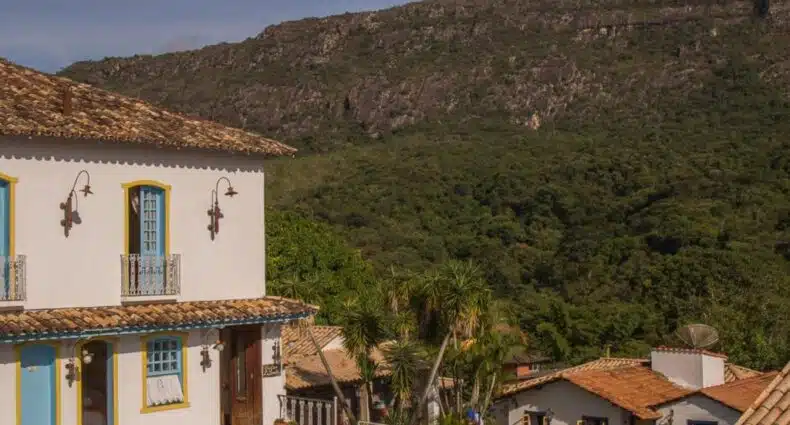 Casarão colonial branco com telhado de cerâmica e vista para montanhas no Pousada Hospedaria da Villa. Representa hotéis em Tiradentes.