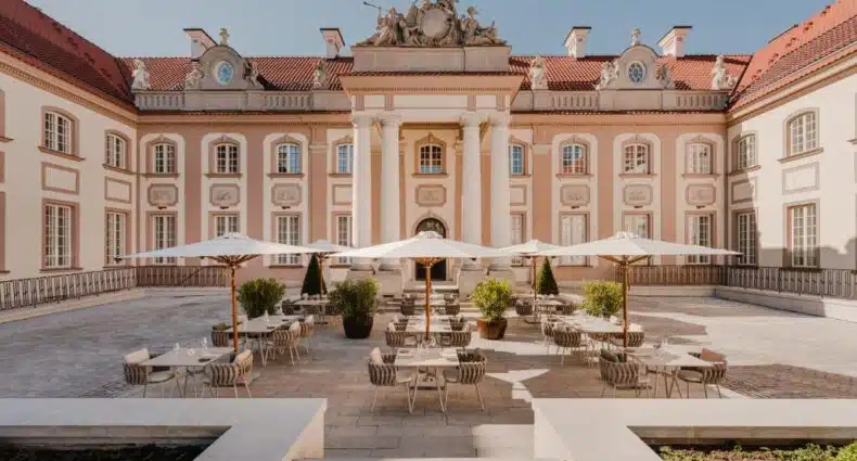 Pátio interno de palácio histórico com mesas e cadeiras para restaurante ao ar livre. Esse é o Hotel Verte, uma das indicações de onde ficar em Varsóvia.