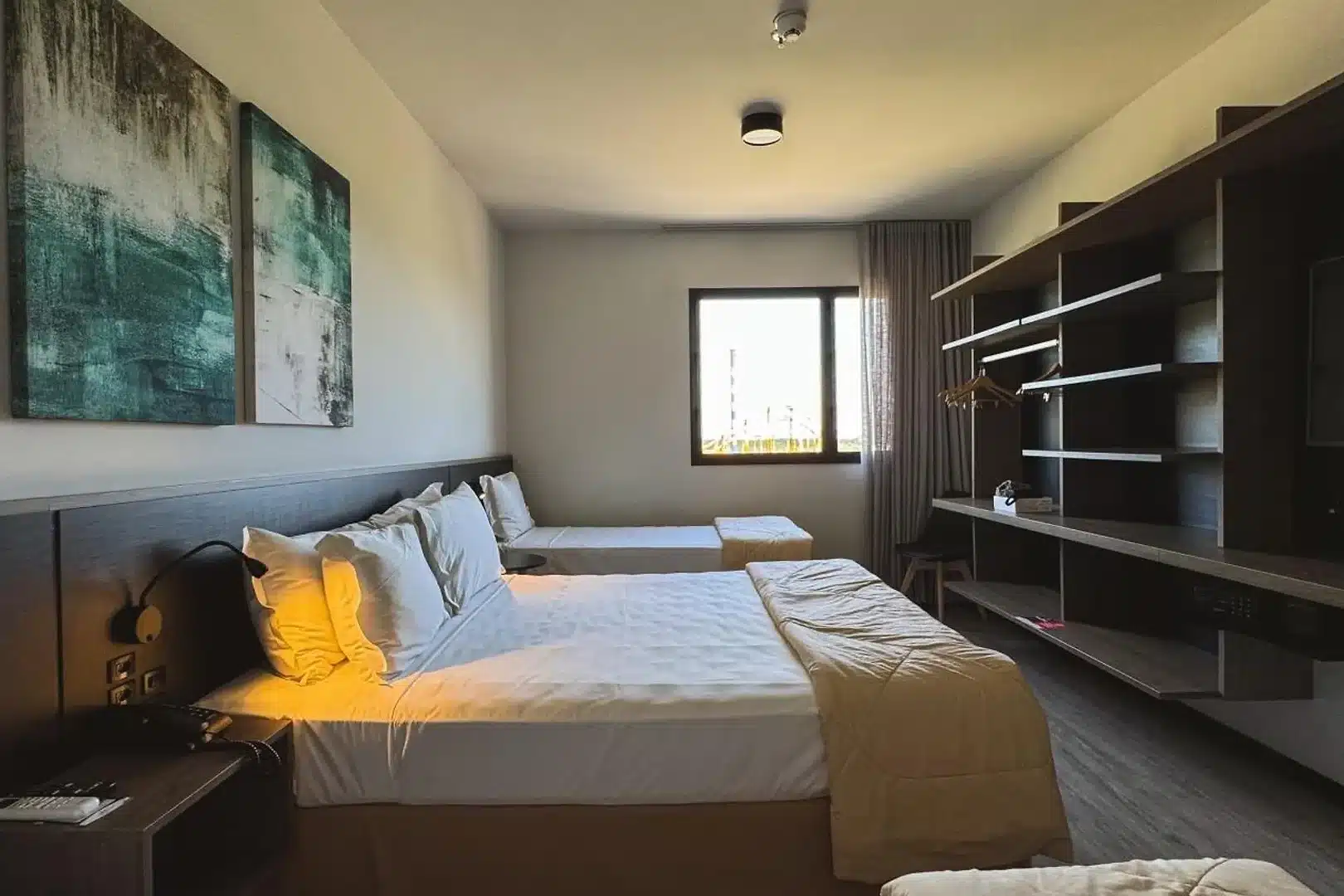 Quarto de hotel moderno com duas camas de solteiro, mesa de trabalho e decoração em tons neutros
