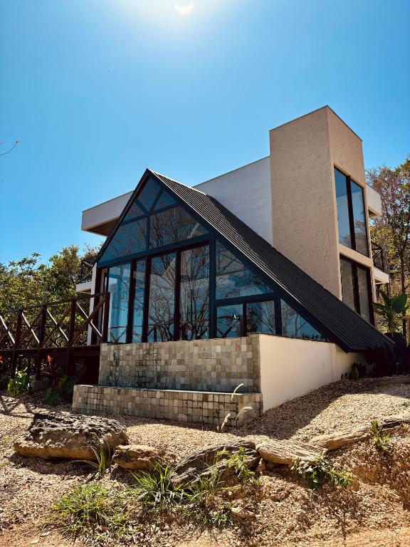 Casa moderna com fachada em vidro e pedra, arquitetura contemporânea em meio à natureza. Ilustra os chalés perto de Goiânia.