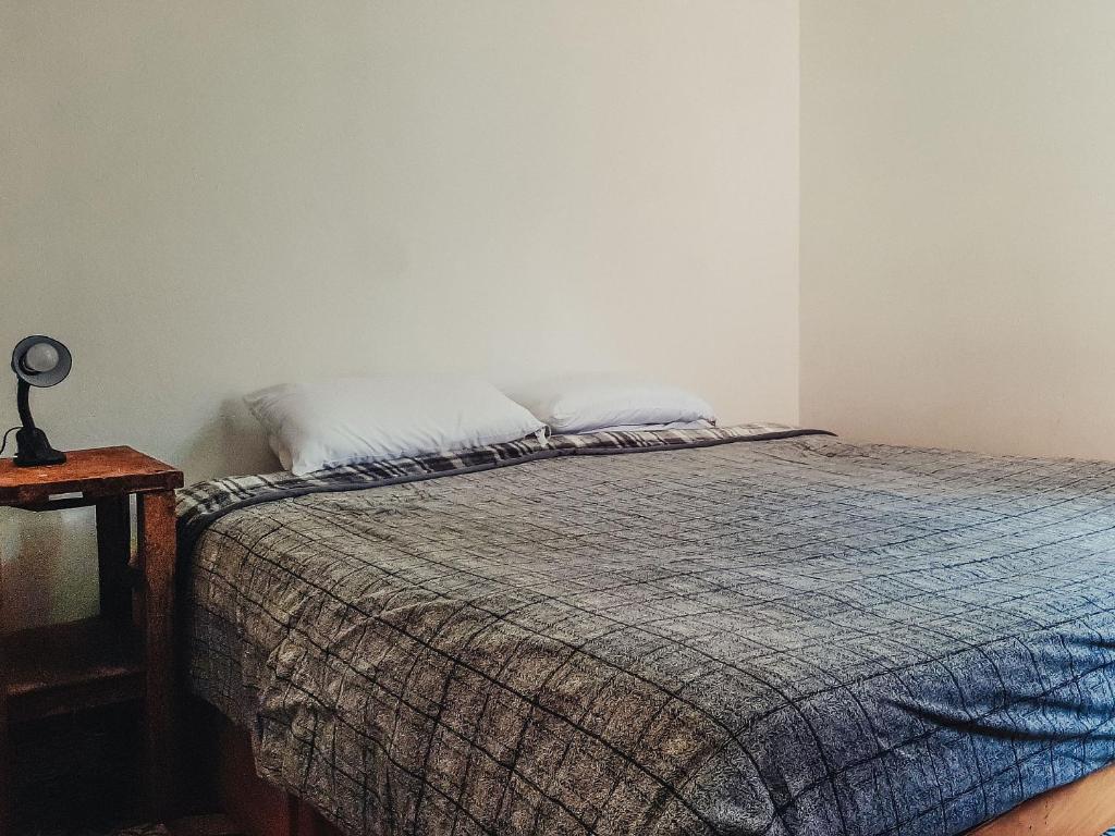 Quarto com cama de solteiro arrumada, colcha xadrez e luminária de mesa rústica do Chalé moderno | Rústico.