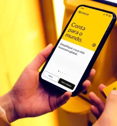 Celular com tela da conta digital Nomad Global e cartão de crédito Visa internacional.